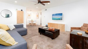 Uma sala de estar moderna com sofá, mesa de centro e televisão na parede.