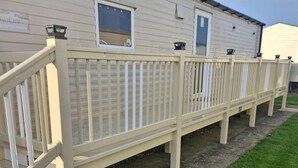 A mobile home with a white exterior, a balcony with a white railing, and two windows. - Meadow View 3-bed Caravan - Sleeps 8 - Petfriendly (Skegness)