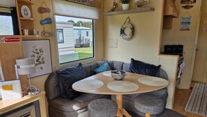 Ein gemütliches Wohnmobil-Interieur mit rundem Tisch, grauen Sitzgelegenheiten, einem Laptop und einem Rauchverbot-Schild.