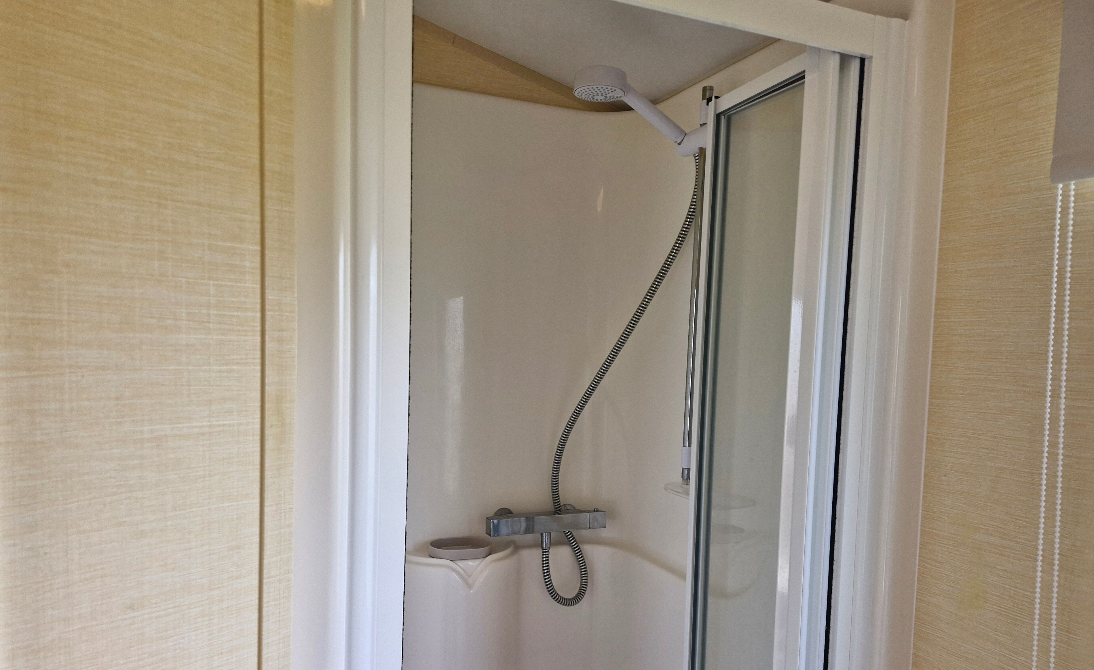 A shower with a glass door and a handheld showerhead.