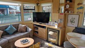 Ein gemütliches Wohnzimmer mit Sofa, Couchtisch, Fernseher und einer kleinen Küchenzeile.