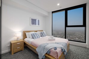 Relax in a stylish room with a large bed, wooden nightstand, and city view.