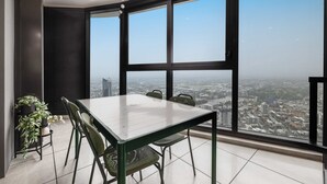 A high-rise room with a large window, a dining table, chairs, and a potted plant.