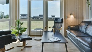 Una sala de estar moderna con un sofá de cuero, un sillón de cuero negro, una mesita y una planta en maceta.