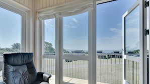 Una habitación con un amplio ventanal corredera que da a una terraza con vistas a un puerto deportivo y barcos.