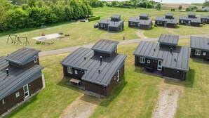 Un camping con varias cabañas, un parque infantil y una zona de picnic.