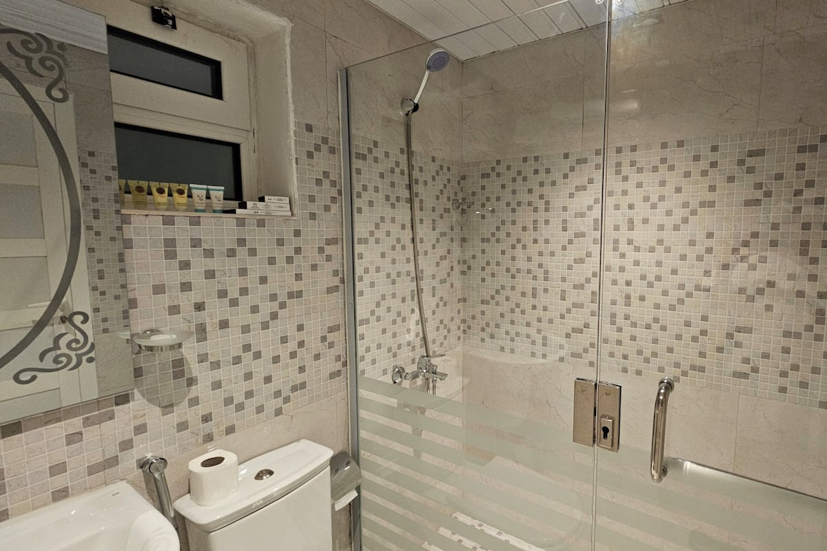 A bathroom with a glass-enclosed shower, a toilet, and a sink.
