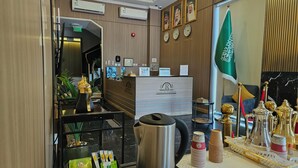 Ein Empfangsbereich mit einem Schreibtisch, einer Flagge, Uhren und einer Kaffeestation.