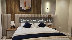 Ein Hotelzimmer mit einem großen Bett, zwei Nachttischen mit Lampen, einer Wandleuchte und einem gerahmten Kunstwerk über dem Bett.