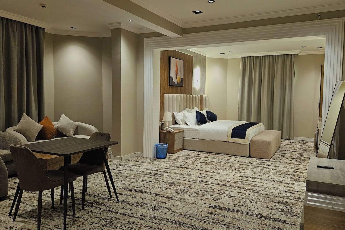 A hotel room with a bed, a desk with a chair, a TV, and a large mirror.