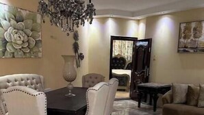 A dining area with a marble floor, a chandelier, and a dining table with chairs.