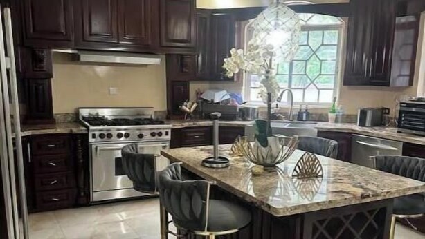 A modern kitchen with dark wood cabinets, stainless steel appliances, and a central island with bar stools.