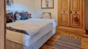 Une chambre à coucher avec un lit, un fauteuil vert, une armoire en bois et un tapis.