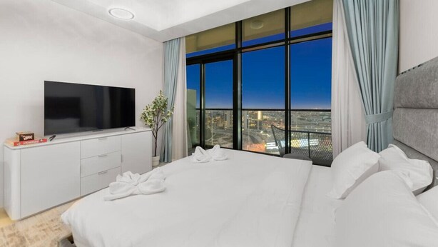 Een moderne hotelkamer met een groot bed, een flatscreen televisie, uitzicht over de stad en een balkon.