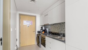 Een moderne keuken met witte kastjes, een roestvrijstalen spoelbak en een betegelde achterwand.