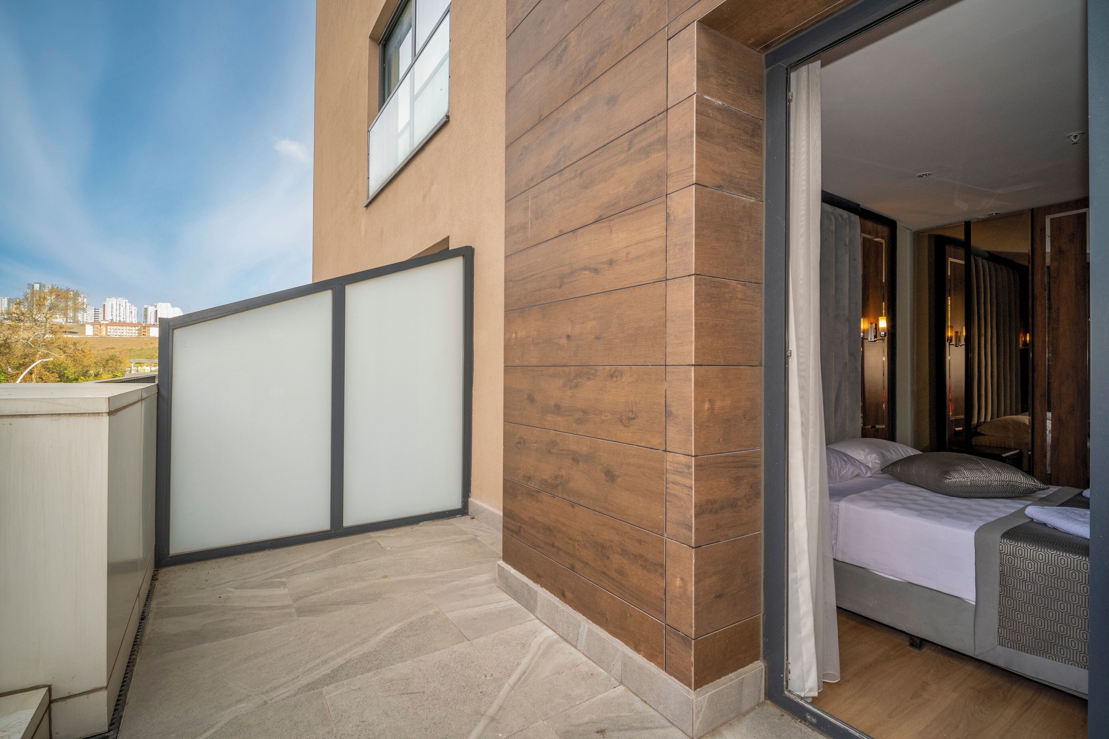Een moderne hotelkamer met een groot raam, een balkon en uitzicht op de stadshemel.