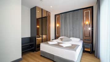 Una habitación de hotel moderna con una cama grande, un área de descanso, un espejo y una mesita de noche.