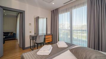 Una habitación de hotel con cama, escritorio, silla y un gran ventanal con cortinas.