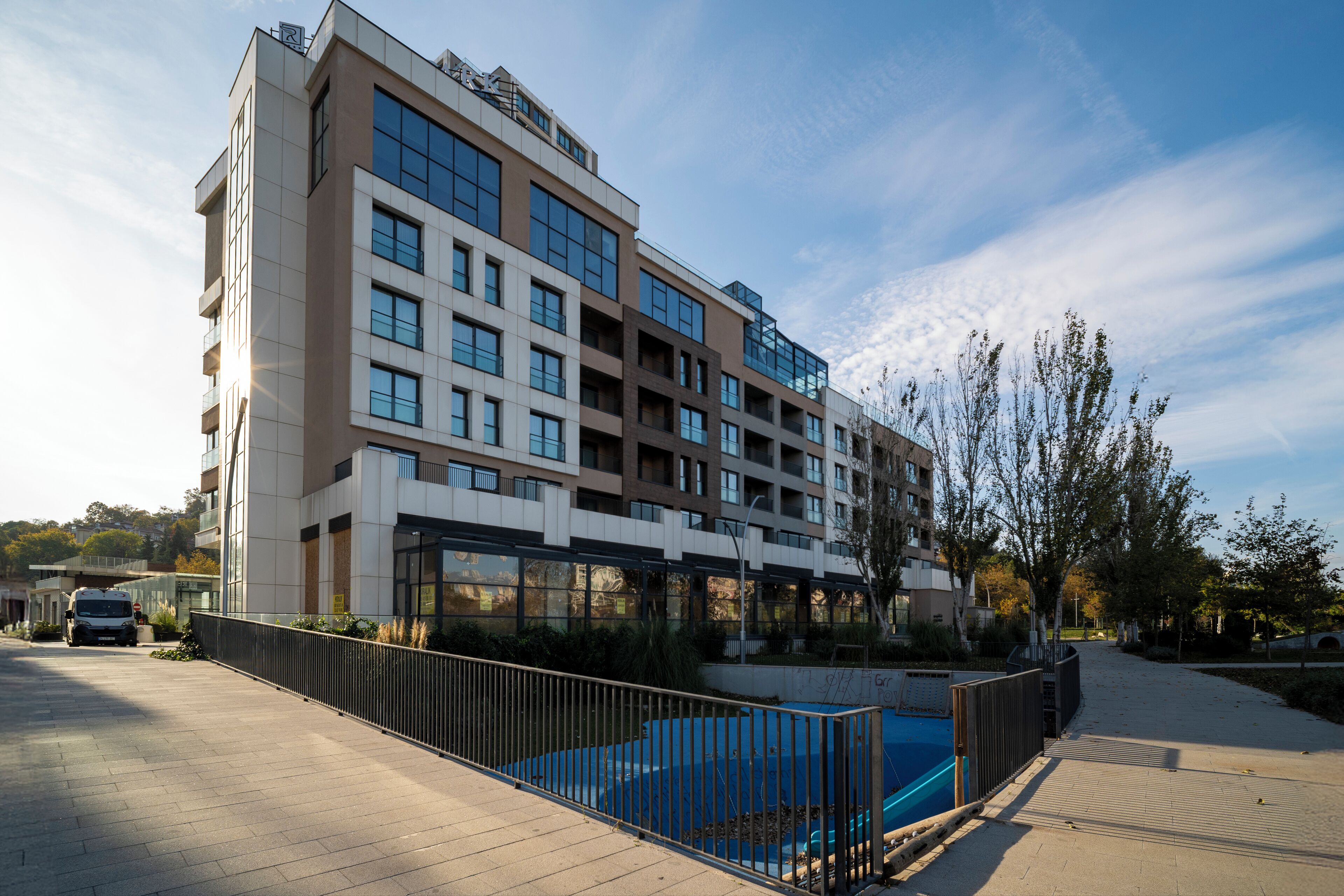 Un hotel de varios pisos con piscina, un paseo cubierto y un estacionamiento.