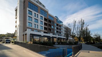 Un hotel de varios pisos con piscina, un paseo cubierto y un estacionamiento.