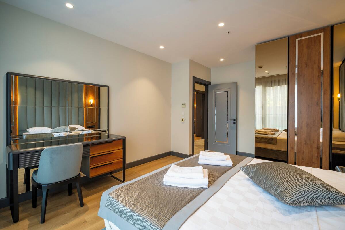 Una habitación de hotel moderna con una cama grande, un escritorio y un espejo.