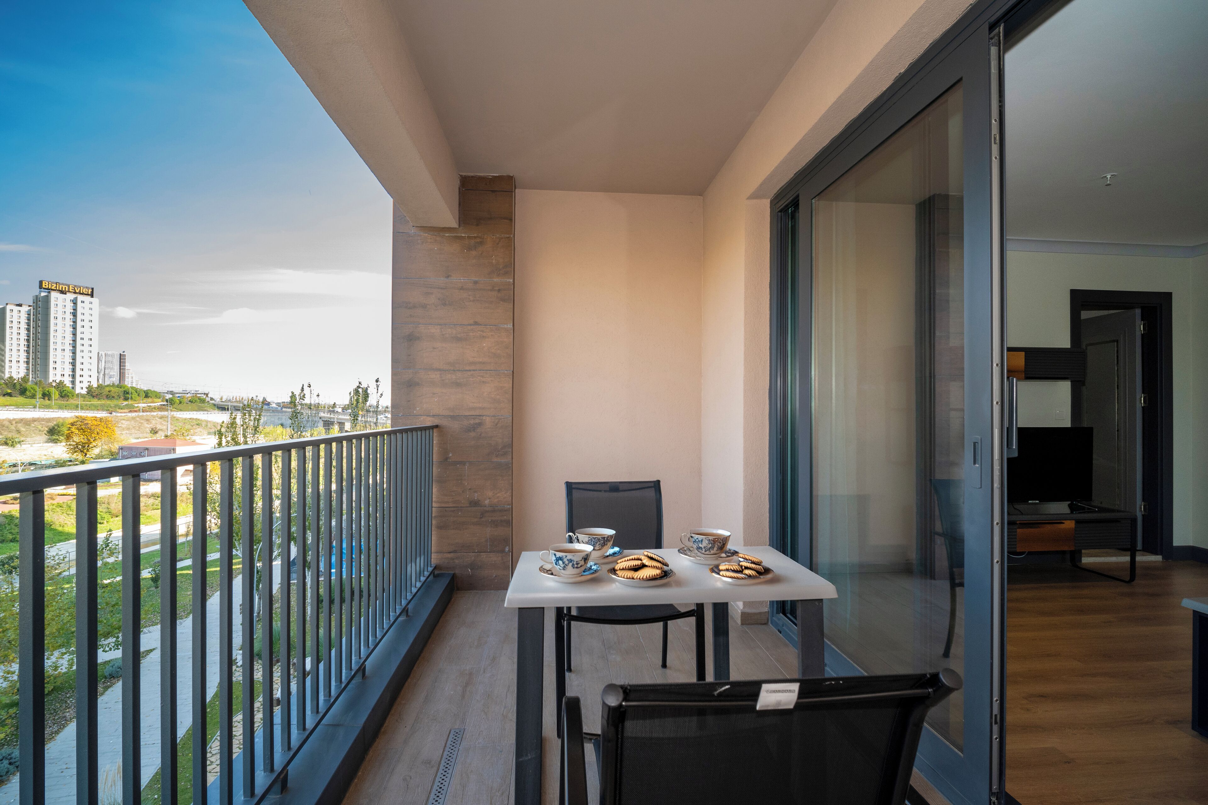 Un balcón con una mesa dispuesta para dos personas, con vistas a un paisaje urbano.