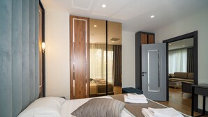 Quarto de hotel moderno com uma cama grande, área de estar separada e vista para a sala de estar.