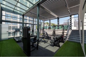 A modern gym with exercise equipment, a treadmill, and a staircase leading to an upper level. - Rusel Park Residence (Istanbul)