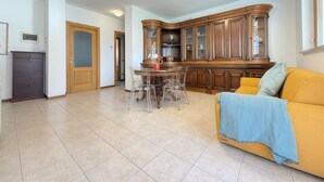 Amplia sala de estar con un sofá amarillo, una mesa de comedor con sillas y un mueble de madera.