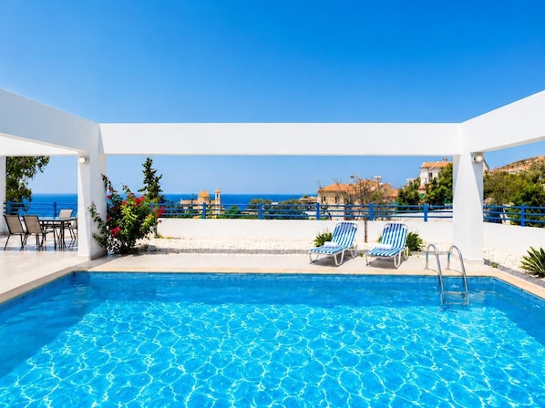 Área da piscina com espreguiçadeiras e vista para o mar.