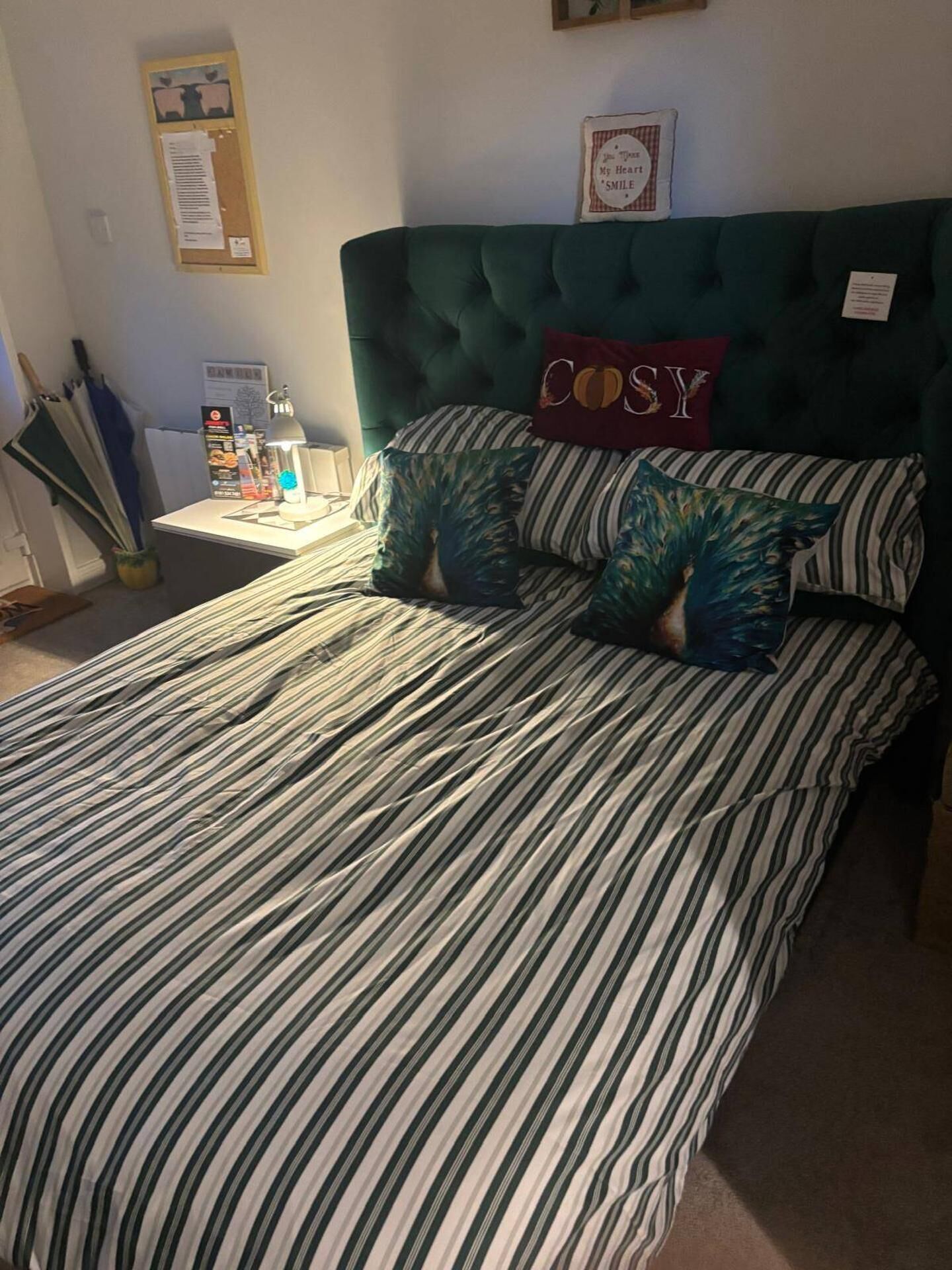 A bed with striped bedding, a tufted headboard, and two pillows with the word 'COSY' on them.