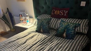 A bed with striped bedding, a tufted headboard, and two pillows with the word 'COSY' on them. - Studio/near Beach/garden/parking/petsok (Sunderland)