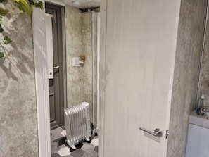 A bathroom with a white door, a radiator, and a tiled floor. - Studio/near Beach/garden/parking/petsok (Sunderland)