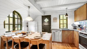 Une cuisine chaleureuse avec un plancher en bois, une table à manger avec des chaises, un réfrigérateur, un lave-vaisselle et une cuisinière.