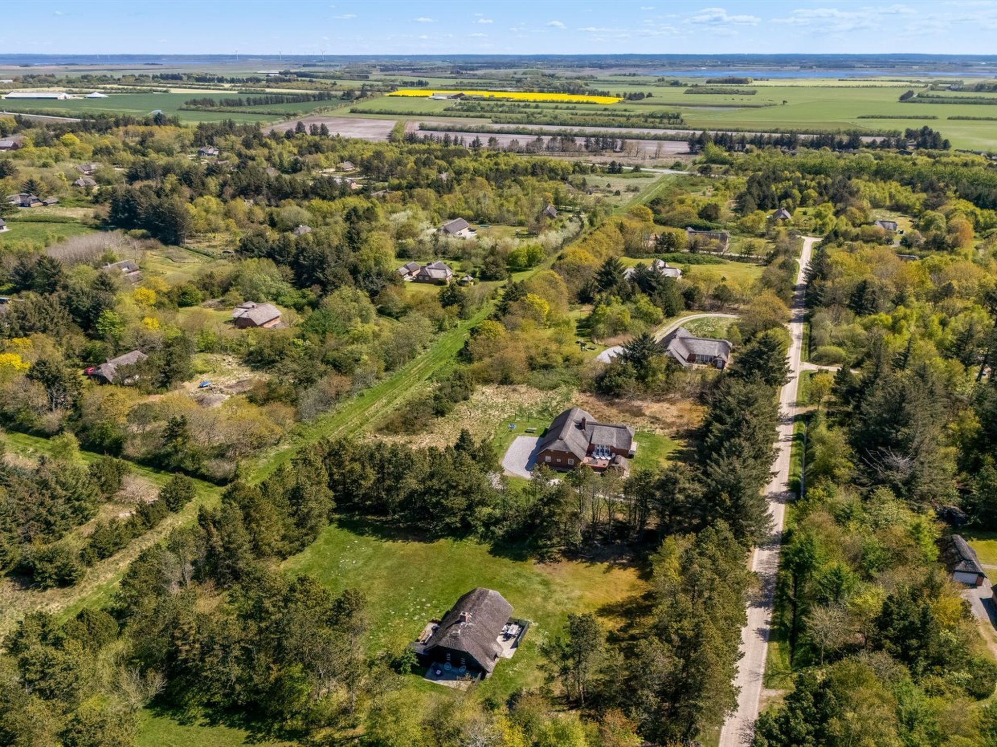 An aerial view of a rural area with scattered houses, a main road, and fields.