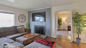 A living room with a fireplace, a sofa, a coffee table, and a potted plant.