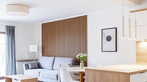 A modern living room with a sofa, a dining table, and a kitchen area. - Native Apartments Barska 13 (Kraków)