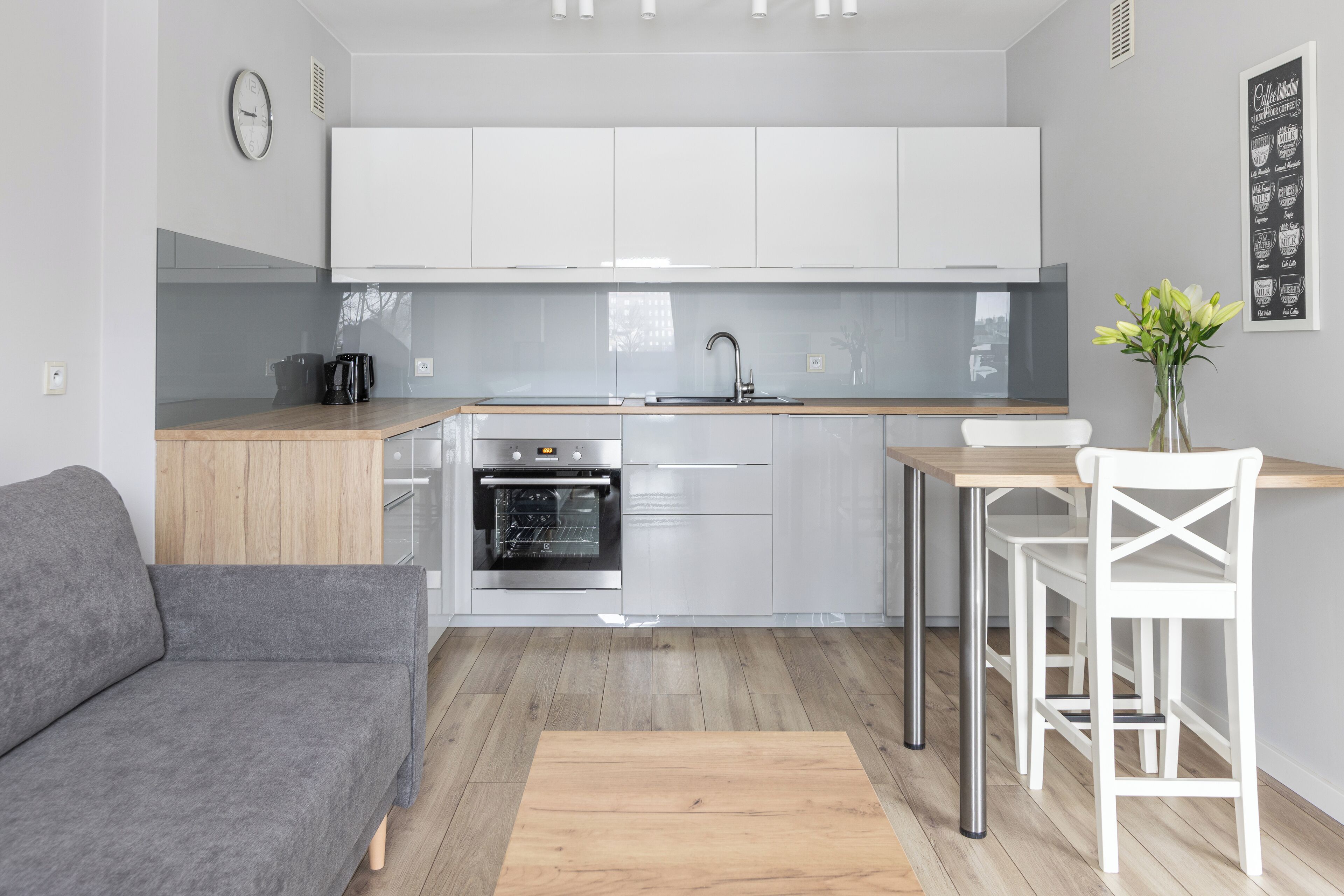 Cocina moderna con alacenas blancas, horno integrado y encimera de madera.
