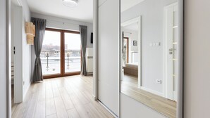 A modern apartment with a large sliding glass door leading to a balcony, a wooden floor, and a large mirror reflecting the interior. - Native Apartments Barska 13 (Kraków)