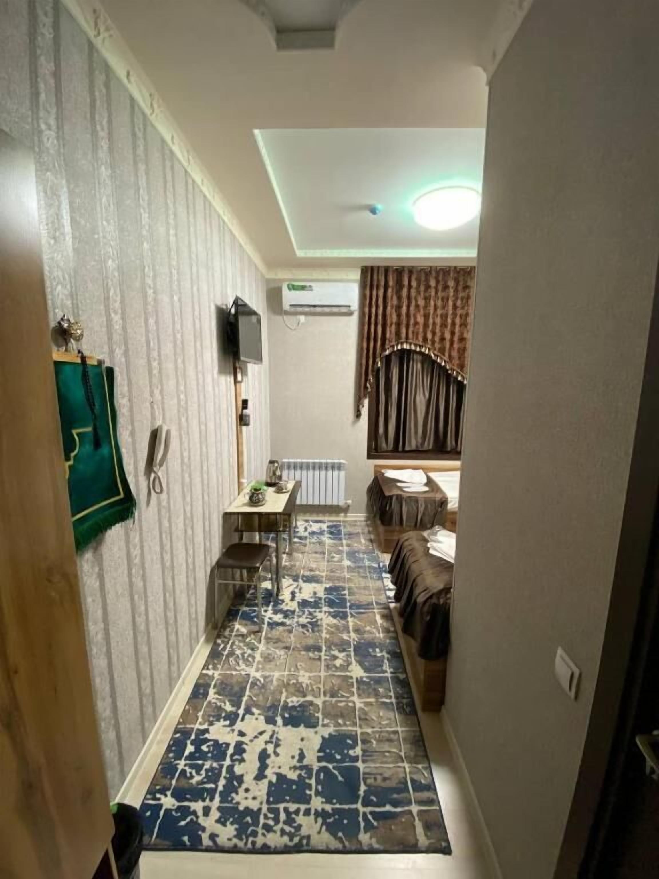 A narrow hallway with patterned flooring leading to a dining area with a table and chairs. An air conditioning unit is mounted on the wall.