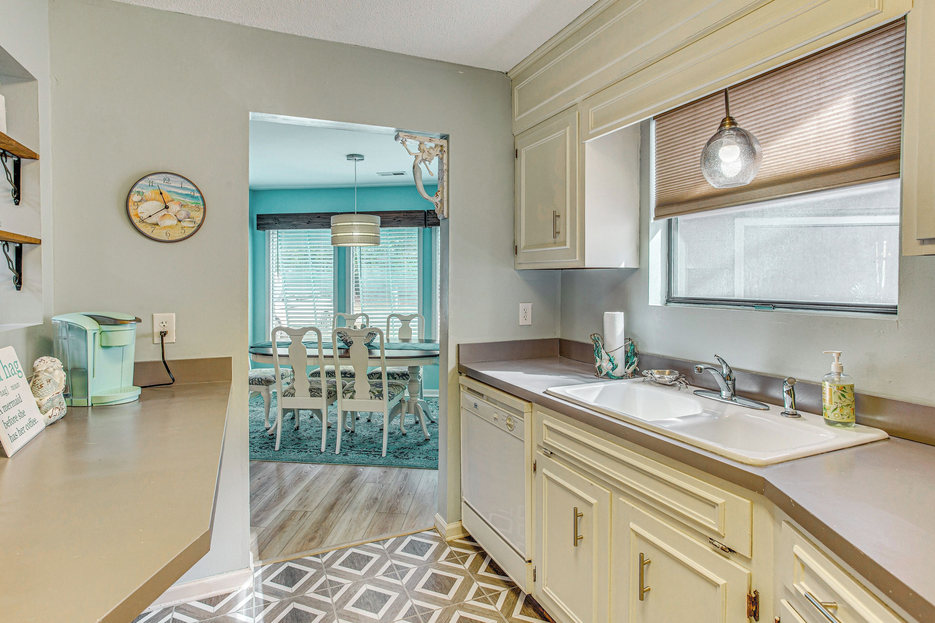 A kitchen with a sink, cabinets, and a clock on the wall.