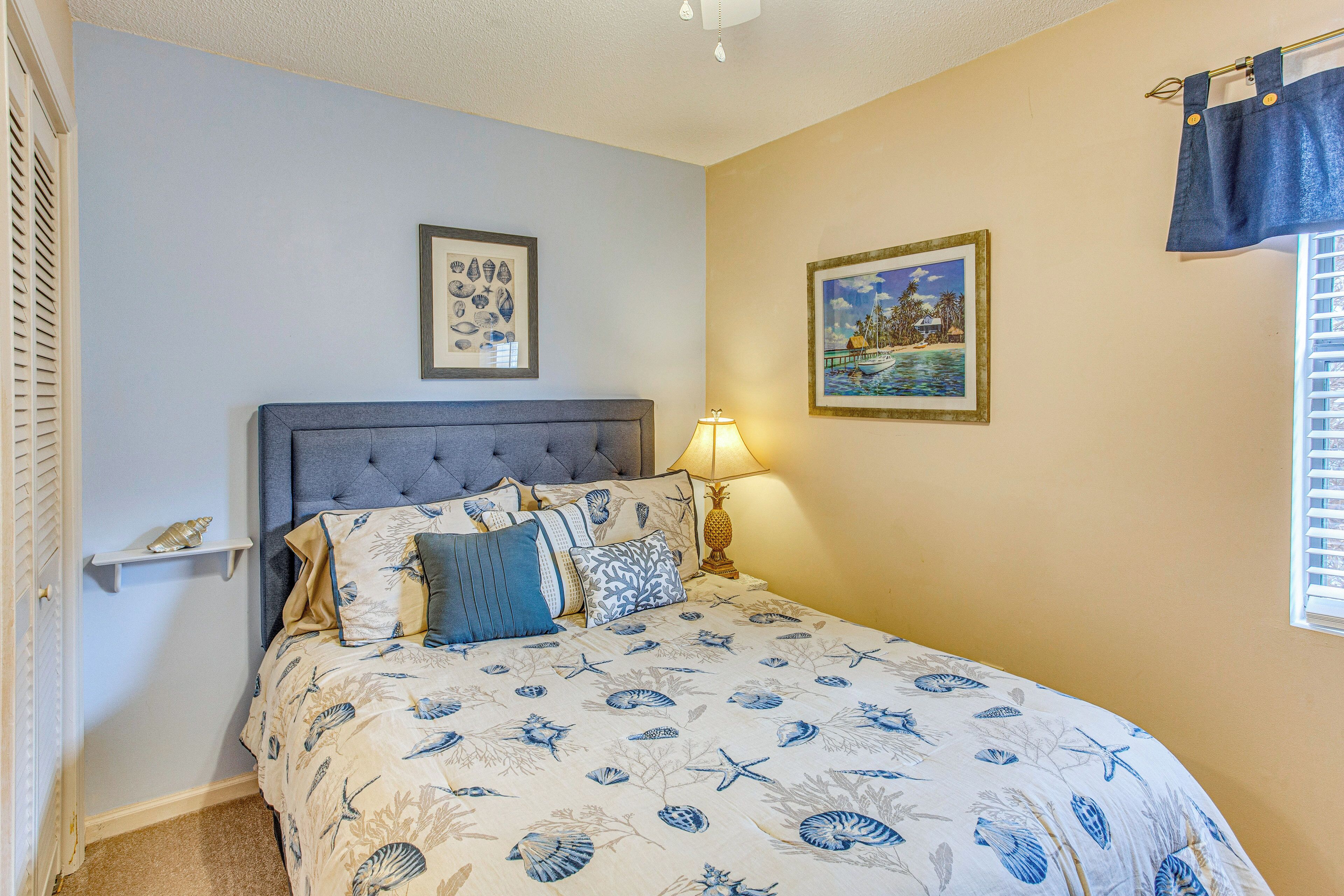 A bedroom with a bed, a nightstand, a lamp, and two framed pictures on the wall.