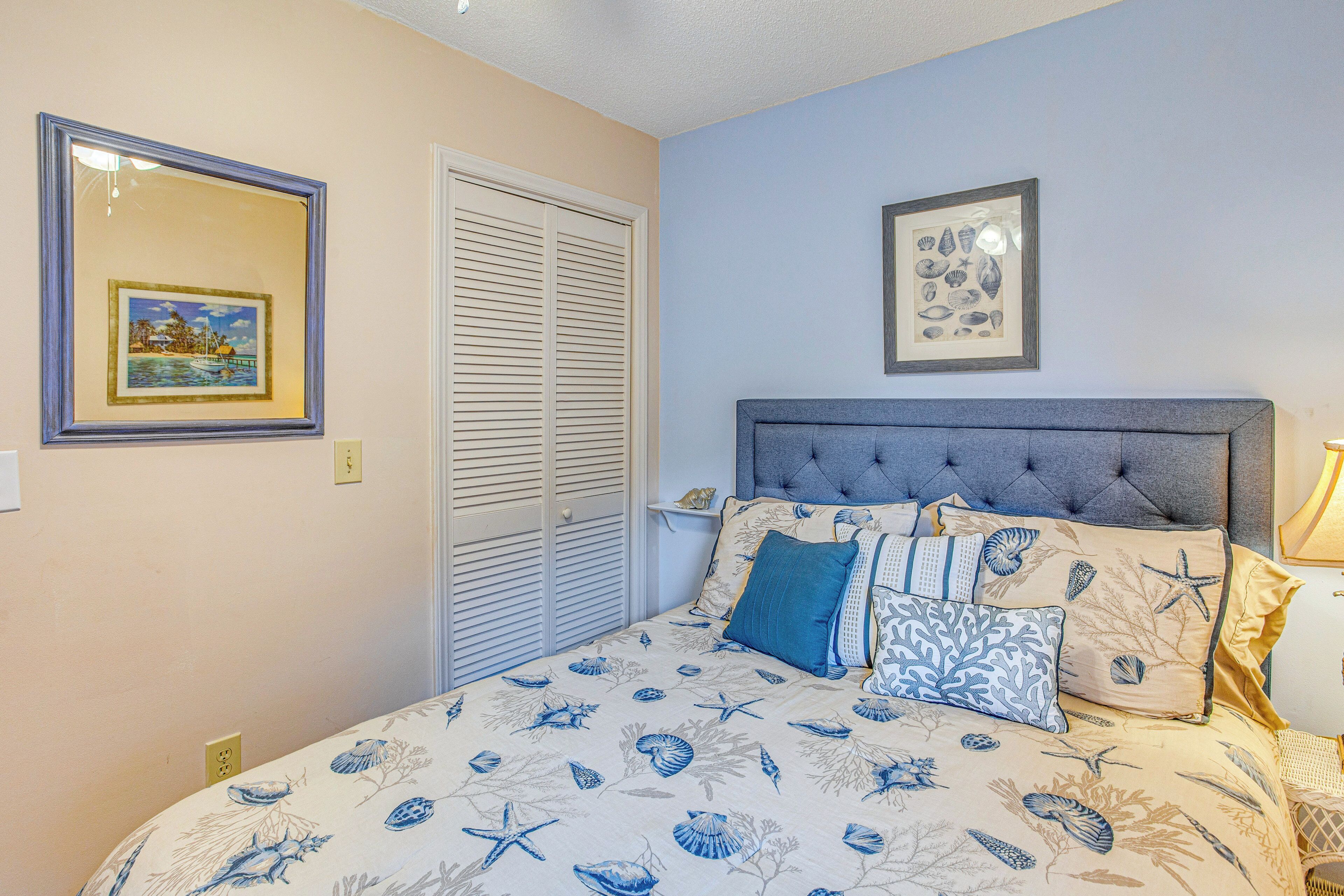 A bedroom with a bed, a headboard, and two framed pictures on the wall.