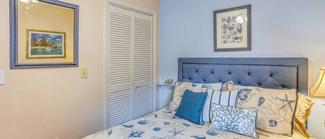 A bedroom with a bed, a headboard, and two framed pictures on the wall.