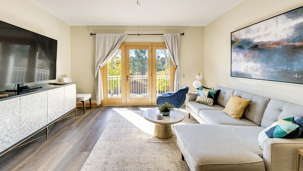 A modern living room with a sofa, coffee table, and a TV on a cabinet. - Condo w/ Balcony > 2 Mi to Angel Fire Resort! (Angel Fire)