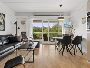 Een moderne woonkamer met een leren bank, een salontafel en een eethoek met stoelen.