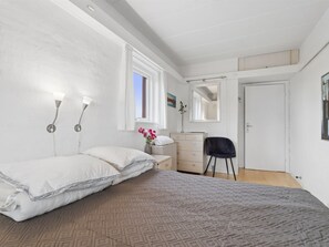 Een slaapkamer met een bed, een kaptafel, een stoel en een raam met gordijnen.