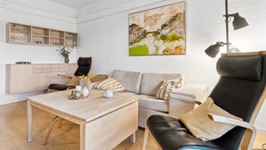 A modern living room with a wooden coffee table, a sofa, a black leather chair, and a painting on the wall. - "Answald" - 6km from the sea by Interhome (Aakirkeby)