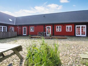 Een rood gebouw met een pannendak en een binnenplaats met kinderaardewerk bestrating.