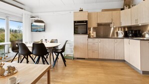 A modern kitchen with wooden cabinets, a built-in oven, and a dining area with a table and chairs. - "Answald" - 6km from the sea by Interhome (Aakirkeby)